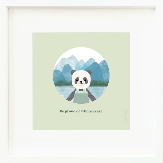 An inspirational print with a graphic of Paxton the panda in front of a mountainous landscape of blue watercolour. The background of the print is jade with the words “Be proud of who you are” in darker green.